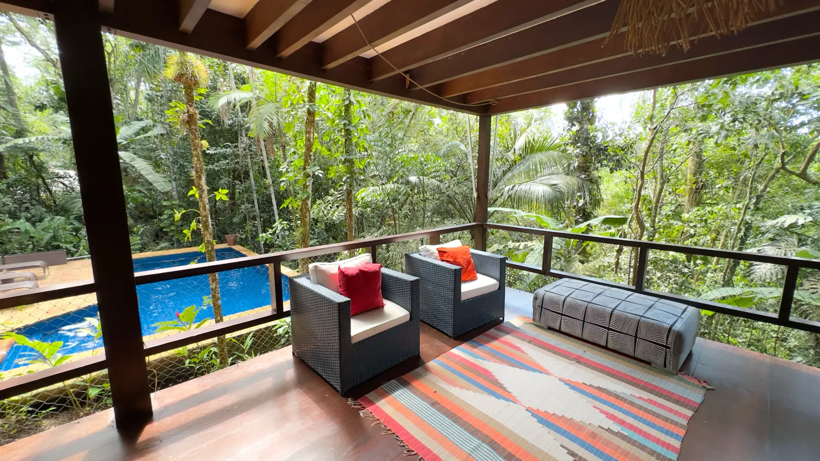 Villa 411 - Casa à venda Condominio Iporanga - Varanda externa com 2 poltronas, sofá com tecido zebrado, tapete no chão e mata atlatica aos fundos